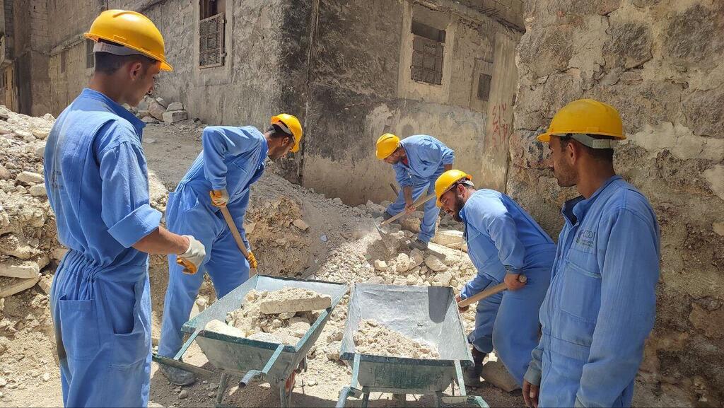 A group of workers remove rubble from a damaged neighbourhood in Syria.